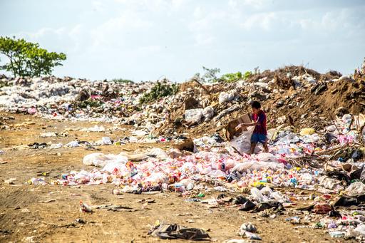 Boy collecting items in a large pile of garbage