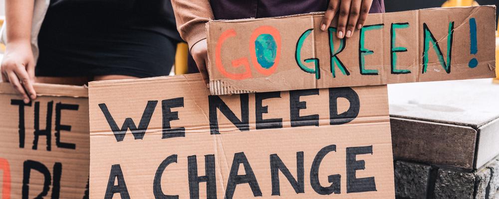 People holding cards saying "we need a change" in a public demonstration