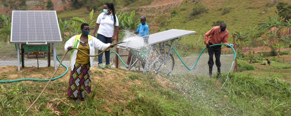 Family in Rwanda irrigating agricultural lands using solar-powered irrigation systems. 