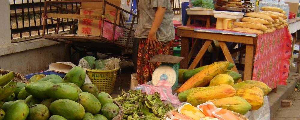 Picture showing a food market in Laos with vegetables, fruits, and nuts