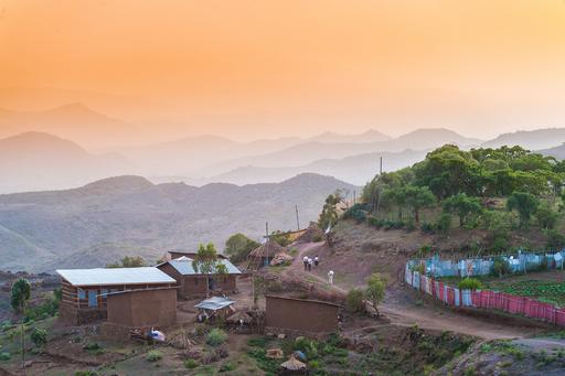 Landscape in rural Ethiopia showing small wooden houses in a sunset